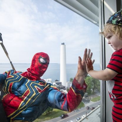 Image of a superhero window washer with child at window