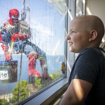 young patient looks on as spiderman cleans window at KGH stie