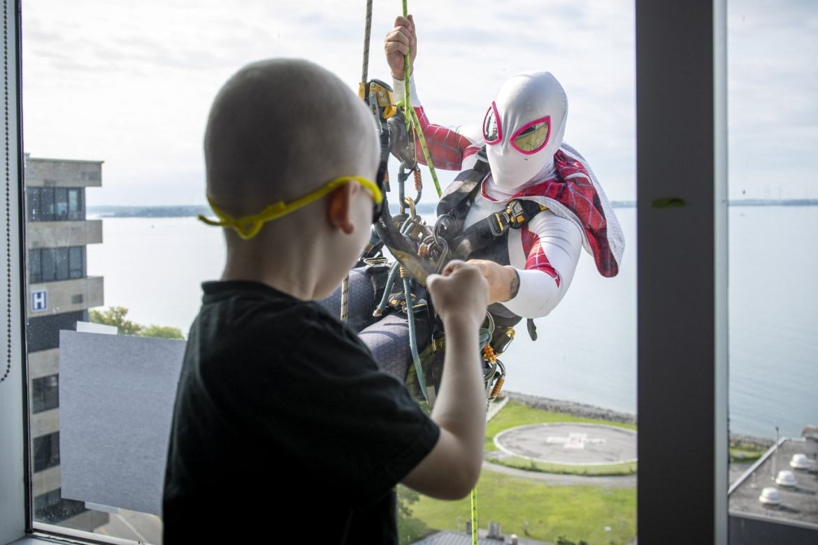 Image of a superhero window washer with child at window