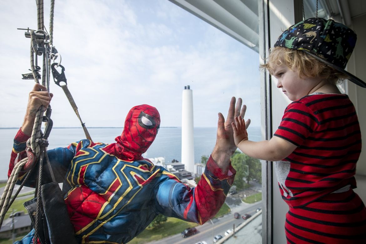 Image of a superhero window washer with child at window