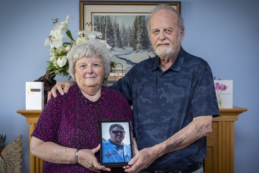 Robert Louis “Robbie” Sherrens parents stand holding a photo of him.